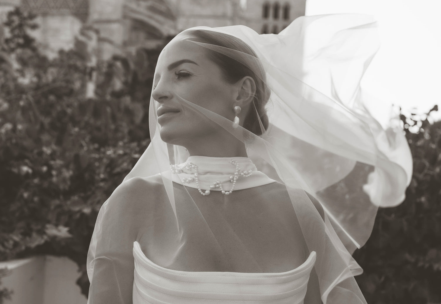 Woman with veil and pearls in front of church